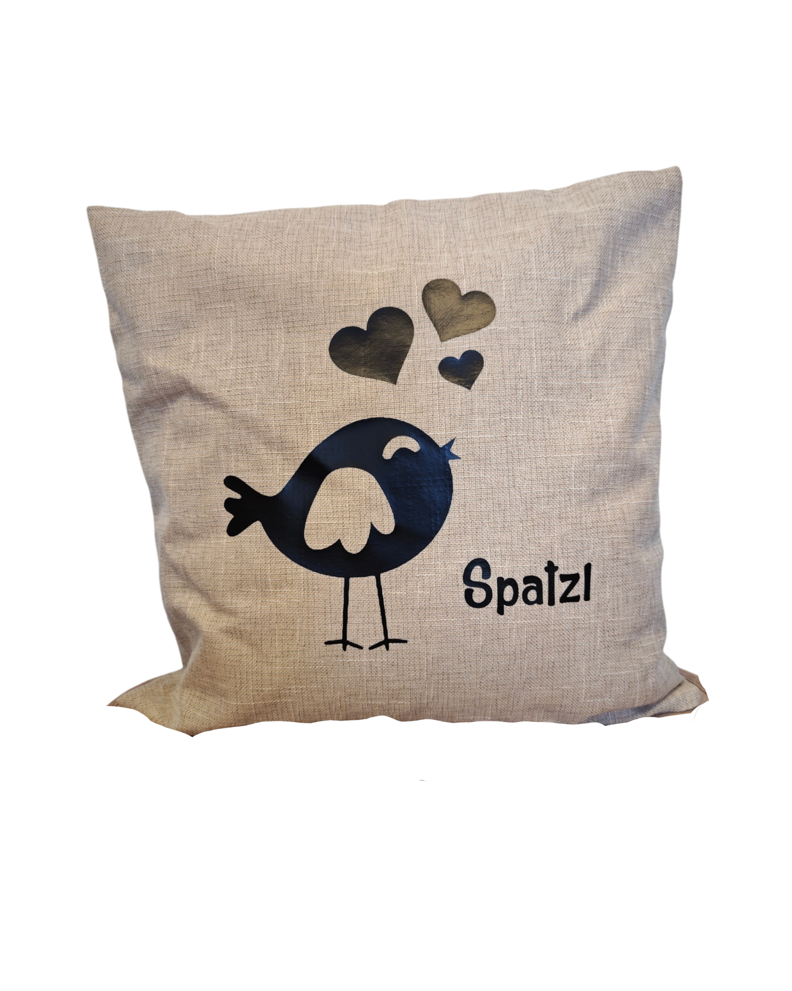Beiger Zirbenpolster, 40x40cm, mit schwarzem Vogel und der Aufschrift Spatzl. 