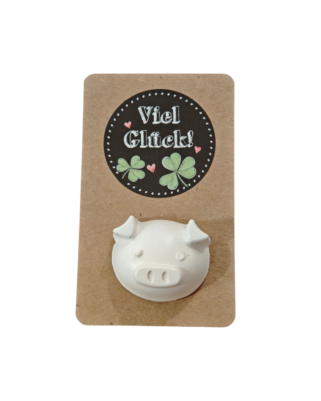 Aus Gips gefertigter Schweinchenkopf auf Kartonpapier mit der Aufschrift Viel Glück. 