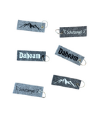 Verschiedene Schlüsselanhänger aus grauem Filz mit unterschiedlichen Motiven. 