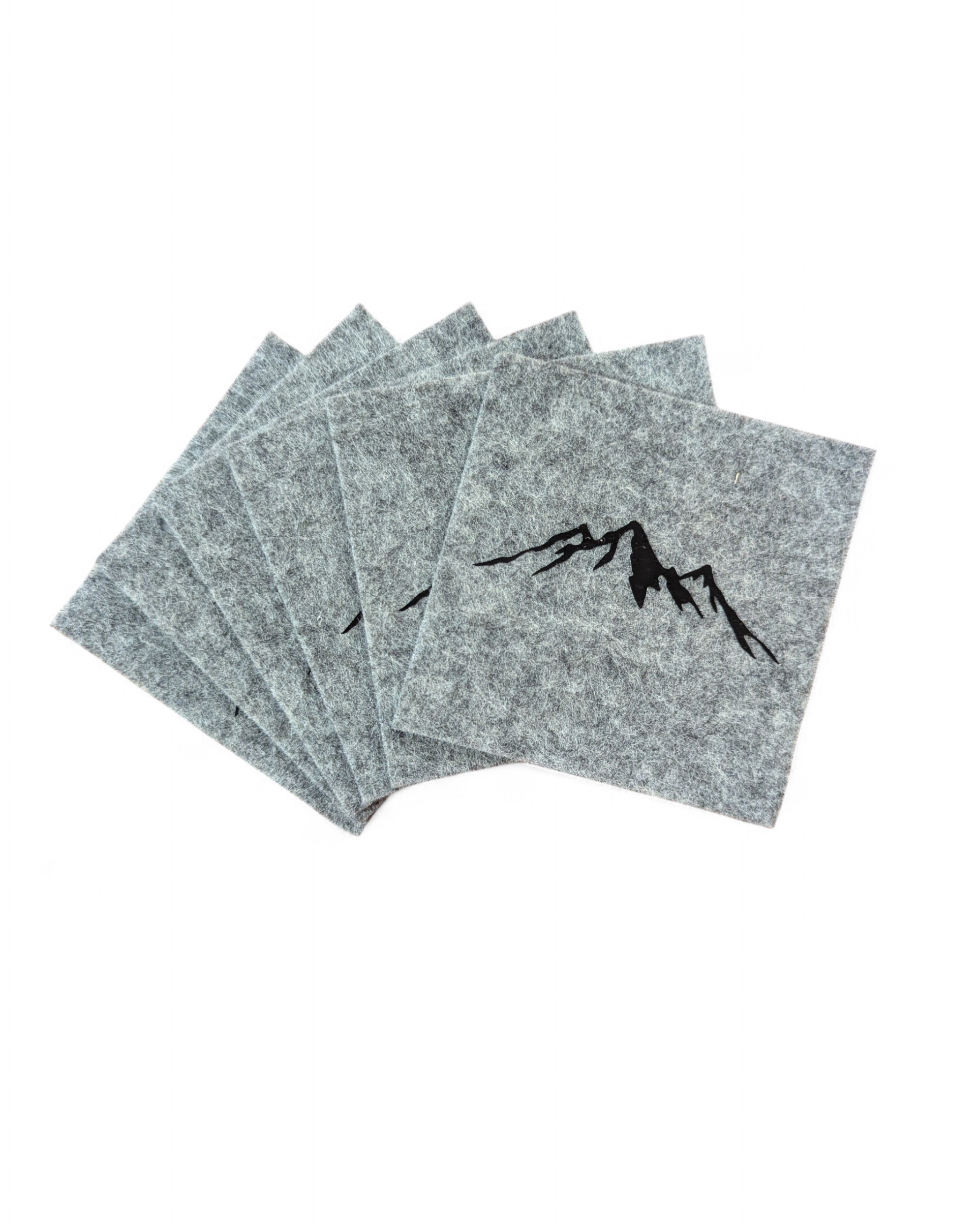 Untersetzer Set mit 6 Stück in hellgrauem Filz mit schwarzem Bergmotiv. 