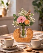 Birkenvase aus gespaltener Birke in der Farbvariante Geölt mit Flachglas und Blumenstrauß auf einem Tisch mit Kaffeetassen. 